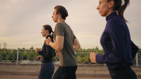 Profisportler-Laufen,-Drei-Personen-Bereiten-Sich-Auf-Den-Marathonlauf-Bei-Sonnenuntergang-Oder-Sonnenaufgang-Vor